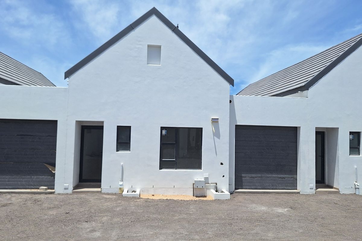 Front elevation of a modern townhouse complex featuring white rendered walls, dark tiled roofs, and integrated garage doors with unfinished ground area.