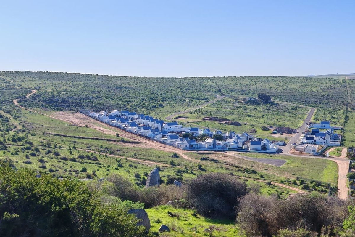 An aerial view of a residential development set within a natural, open landscape with established road infrastructure.