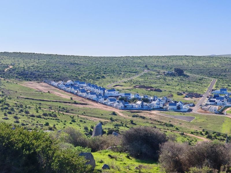 An aerial view of a residential development set within a natural, open landscape with established road infrastructure.