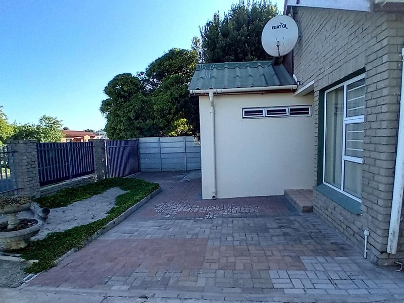 Rear exterior area featuring brick paving, perimeter fencing, and a satellite dish mounted on the side of the house.