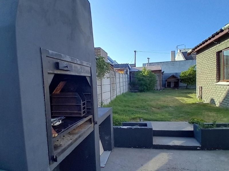 Rear garden area featuring a built-in braai, concrete patio, and perimeter walling, providing a functional outdoor entertainment space.