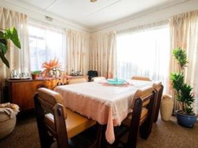 A bright dining room featuring large windows with floor-to-ceiling curtains, offering a functional space for family meals.
