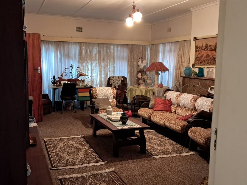 A spacious living room featuring a stone fireplace and large windows, offering a traditional layout with potential for modern updates.