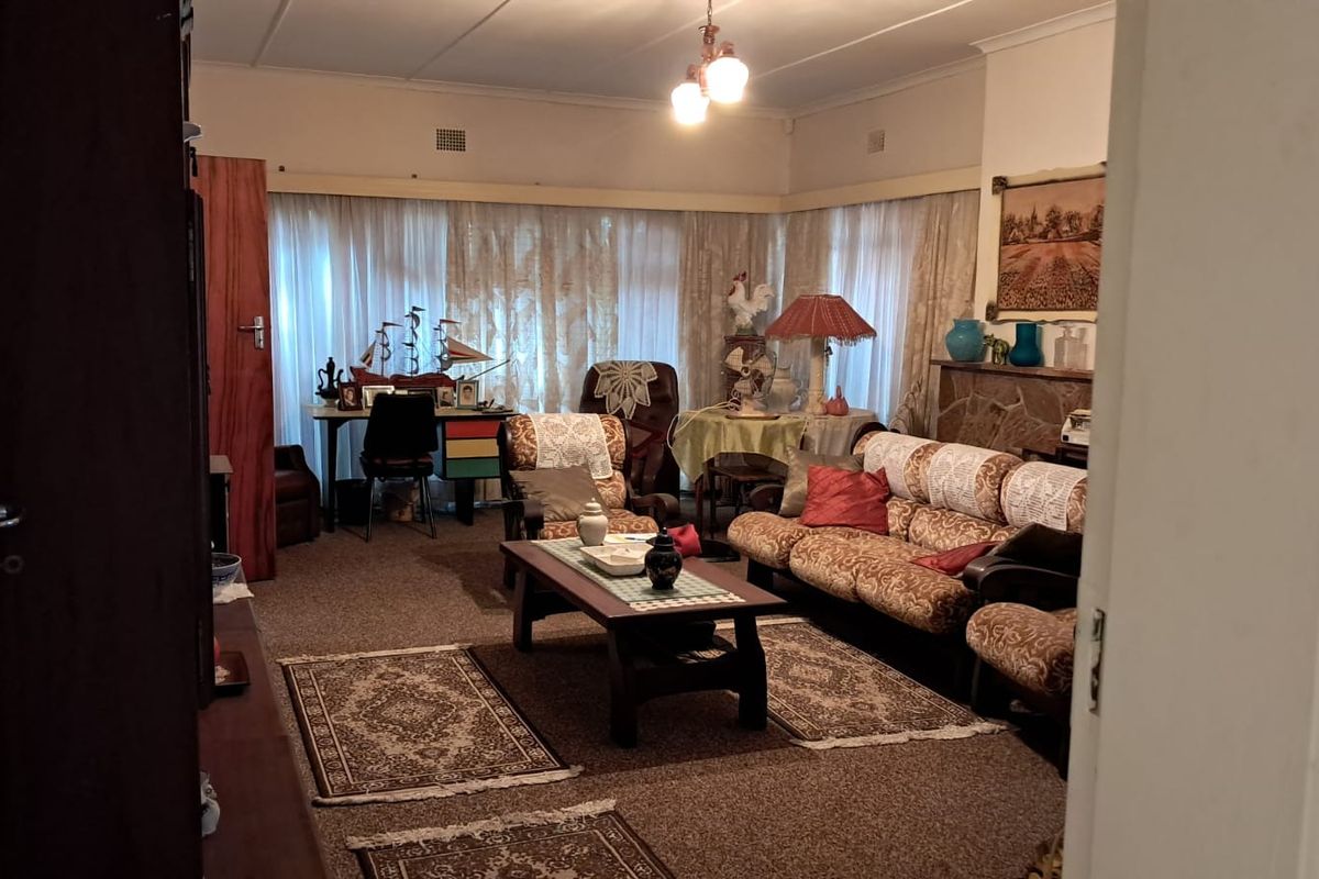 A spacious living room featuring a stone fireplace and large windows, offering a traditional layout with potential for modern updates.