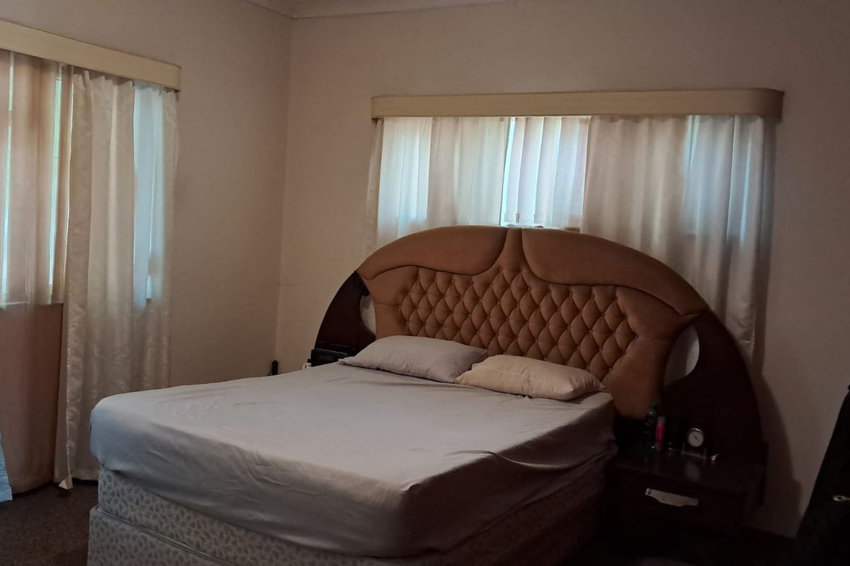 A standard bedroom featuring carpeted flooring and dual window treatments with curtain rails.