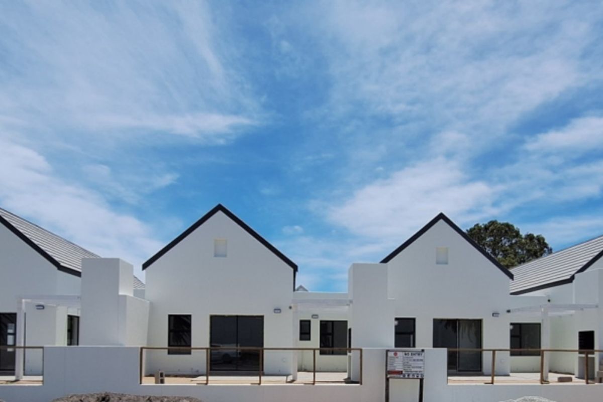 A row of modern townhouse units featuring pitched roofs, white facades, and private patio areas with timber railings.