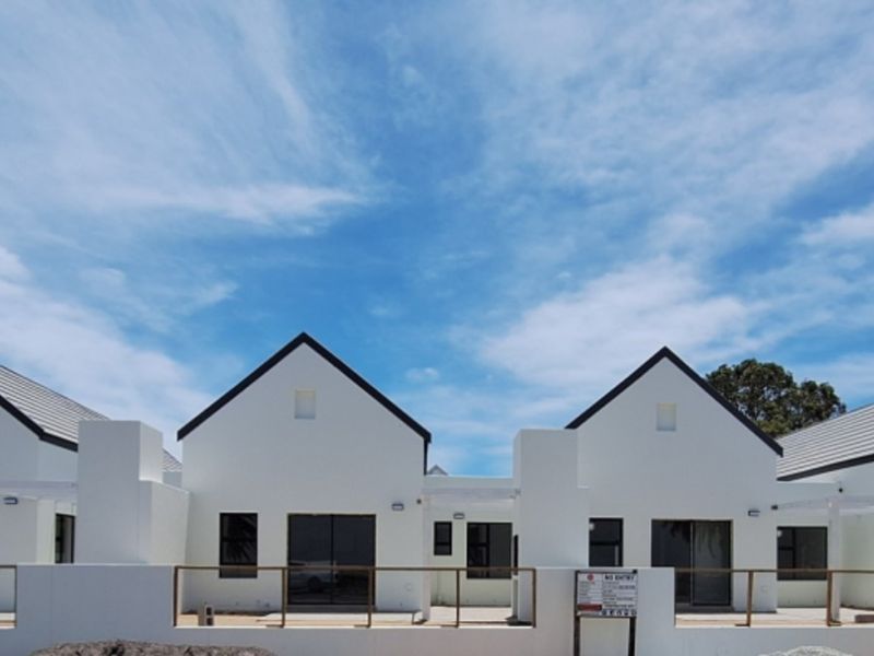 A row of modern townhouse units featuring pitched roofs, white facades, and private patio areas with timber railings.