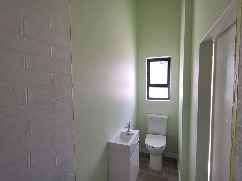 A compact guest bathroom featuring a modern vanity basin, toilet, and neutral tiled finishes.