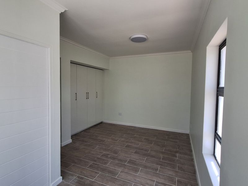 A clean, empty bedroom featuring modern tiled flooring, built-in cupboards, and neutral wall finishes, ready for personalization.