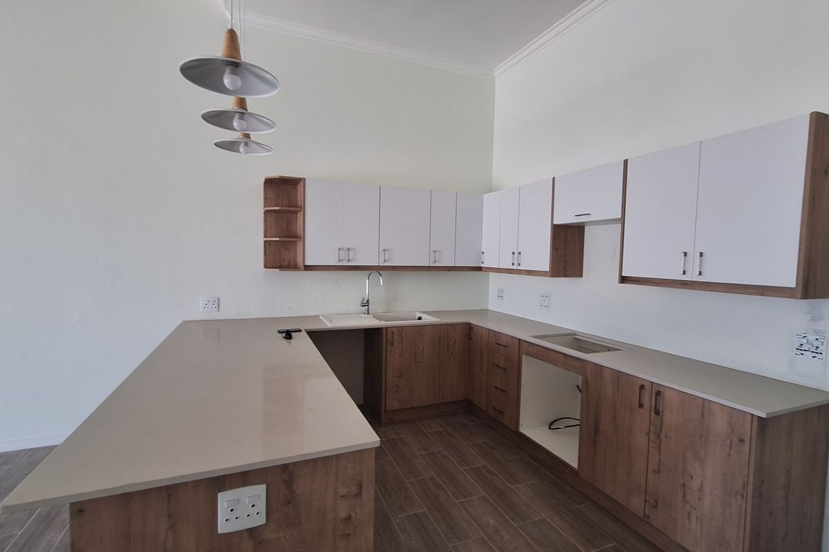 Modern kitchen featuring wood-tone and white cabinetry, quartz countertops, a central island, and tiled flooring. The space is ready for appliance installation.
