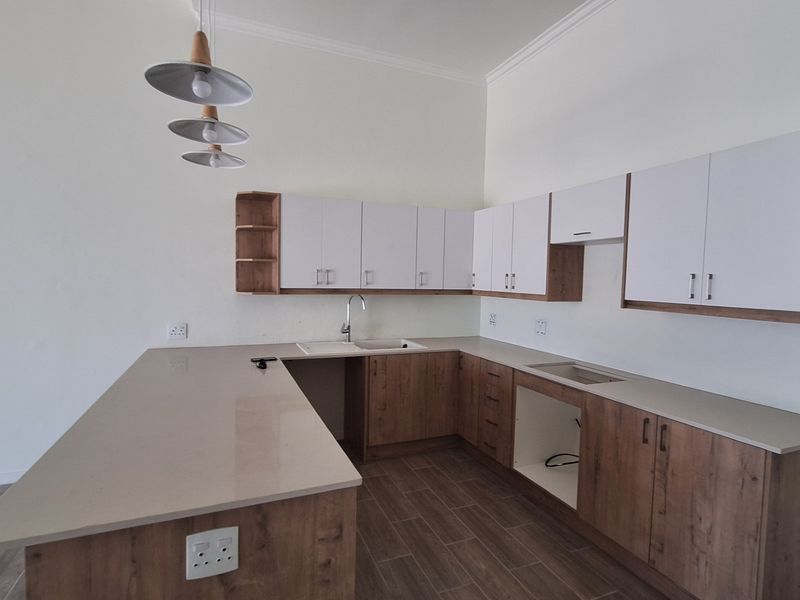 Modern kitchen featuring wood-tone and white cabinetry, quartz countertops, a central island, and tiled flooring. The space is ready for appliance installation.