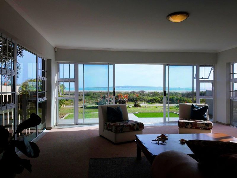 Spacious living room featuring large sliding glass doors that provide abundant natural light and direct views of the garden and ocean.