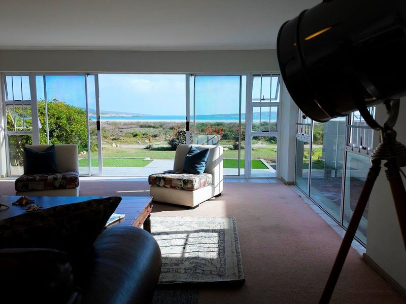Spacious living room featuring large sliding glass doors that provide expansive views of the garden and coastline.