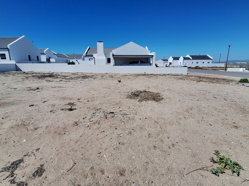 A vacant residential plot of land situated in a developed estate, featuring a boundary wall and direct street access.