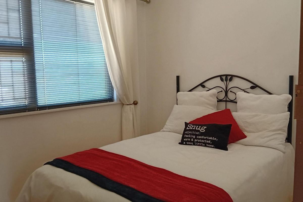 A compact bedroom featuring a window with venetian blinds and neutral wall finishes.
