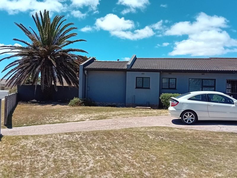 Front exterior view of a single-story house featuring a concrete driveway, tiled roof, and perimeter boundary wall.