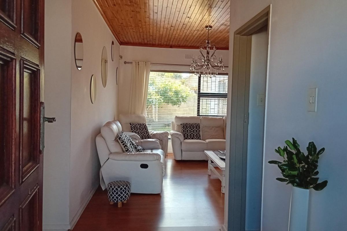 A living room featuring a timber-clad ceiling, chandelier lighting, and laminate flooring, viewed from the entrance hallway.