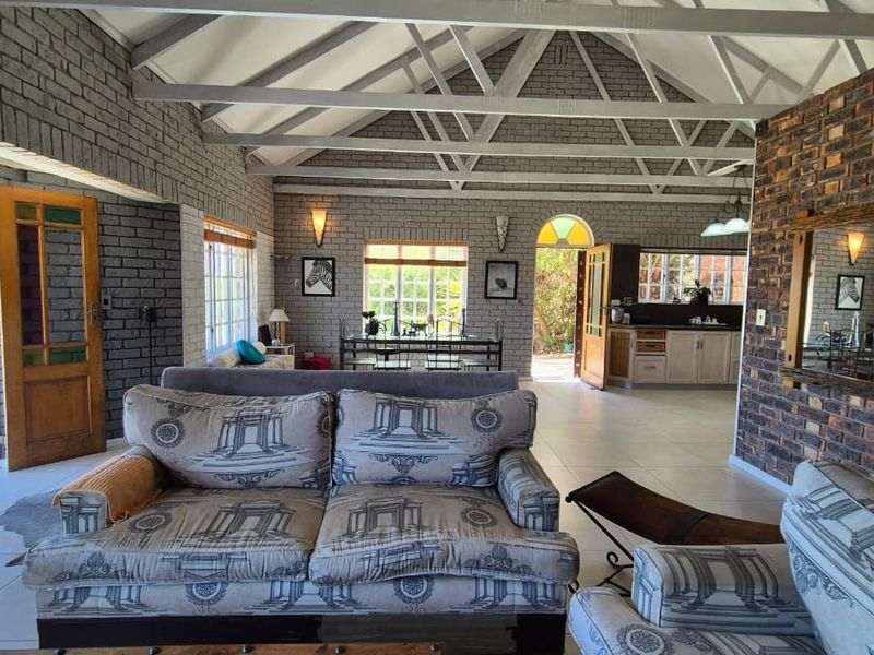 Spacious open-plan living area featuring exposed brick walls, vaulted ceilings with timber trusses, and direct access to the outdoor patio.