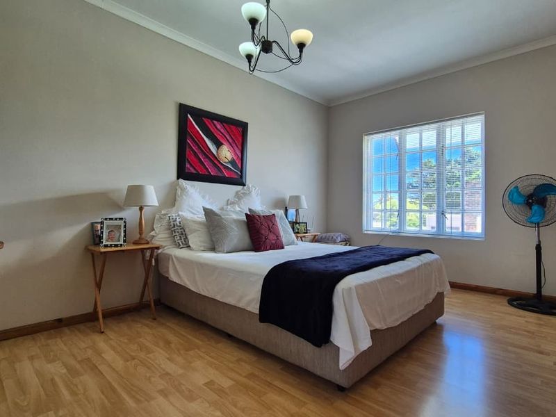 A well-maintained bedroom featuring laminate flooring, a built-in wardrobe, and a multi-pane window allowing for natural light.