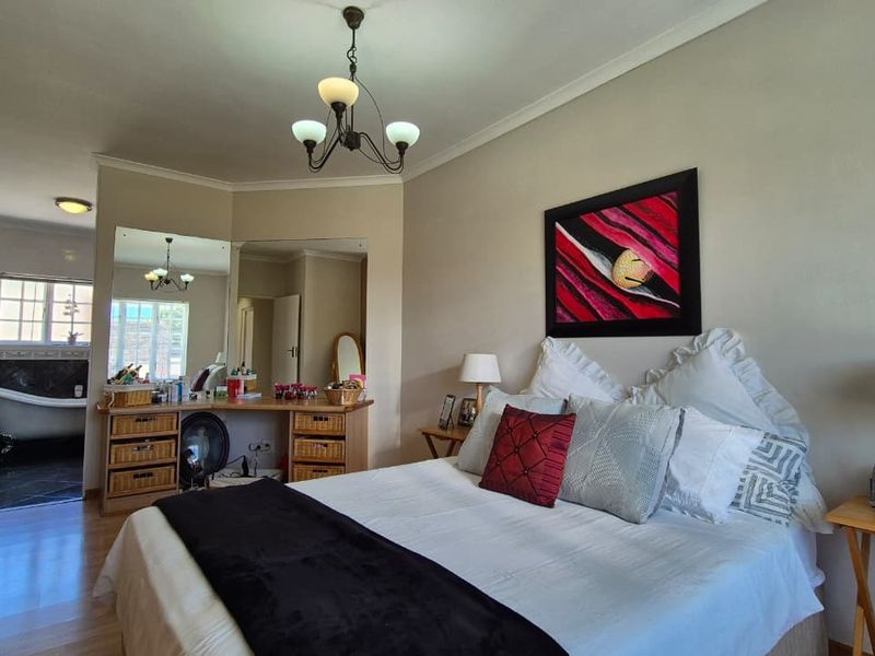 Spacious bedroom featuring laminate flooring, a built-in vanity area, and direct access to an en-suite bathroom with a classic claw-foot tub.