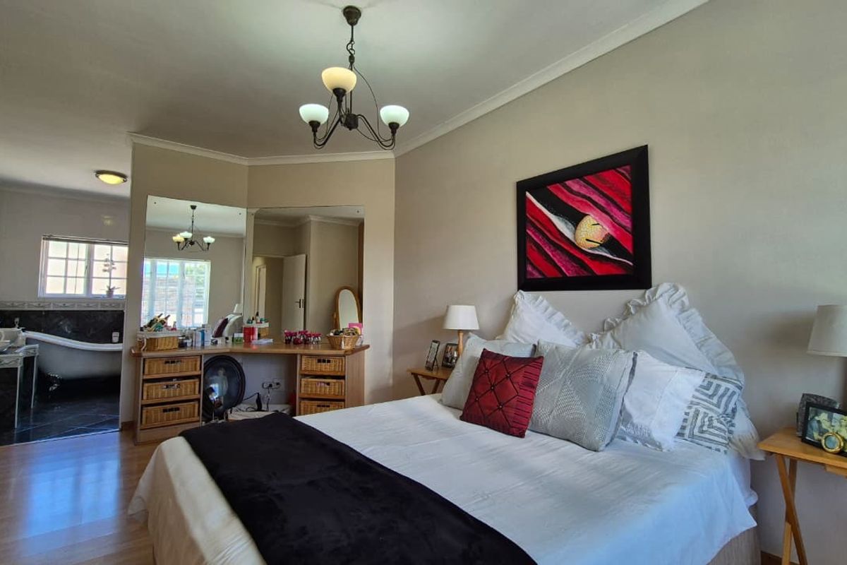 Spacious bedroom featuring laminate flooring, a built-in vanity area, and direct access to an en-suite bathroom with a classic claw-foot tub.