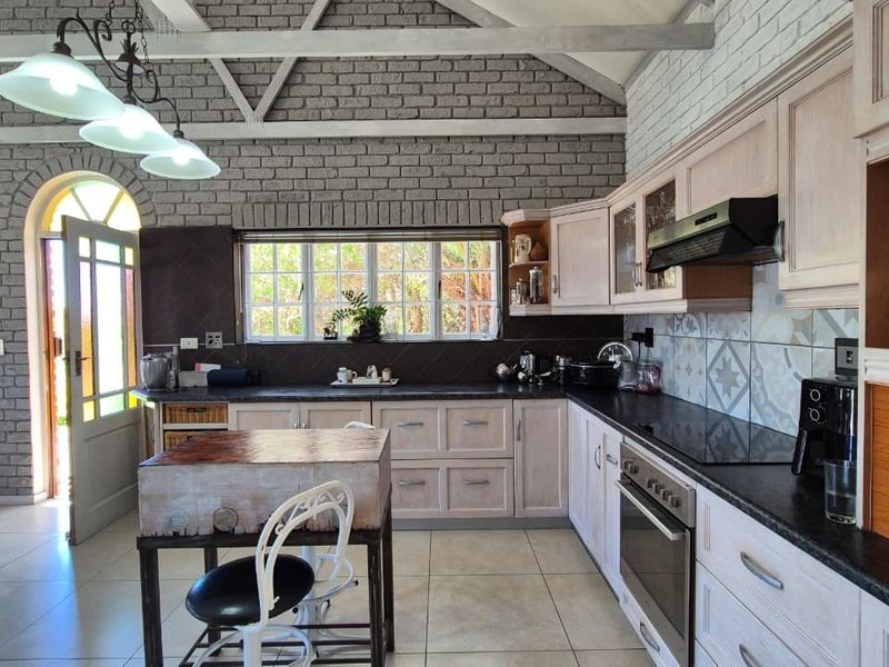 Spacious kitchen featuring vaulted ceilings, exposed brick walls, built-in cabinetry, and modern appliances, offering a unique blend of rustic charm and functional design.