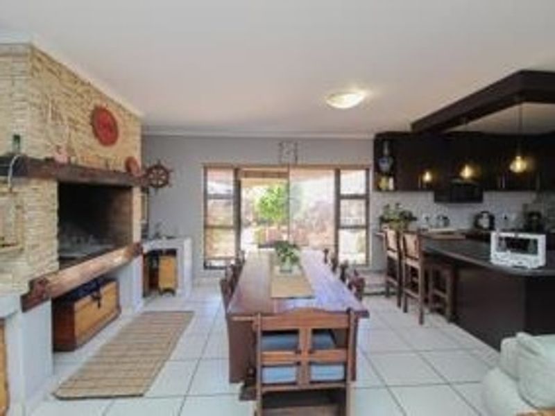 Open-plan living and kitchen area featuring a stone-clad built-in fireplace, dark cabinetry, kitchen island, and direct access to the outdoor patio through sliding doors.