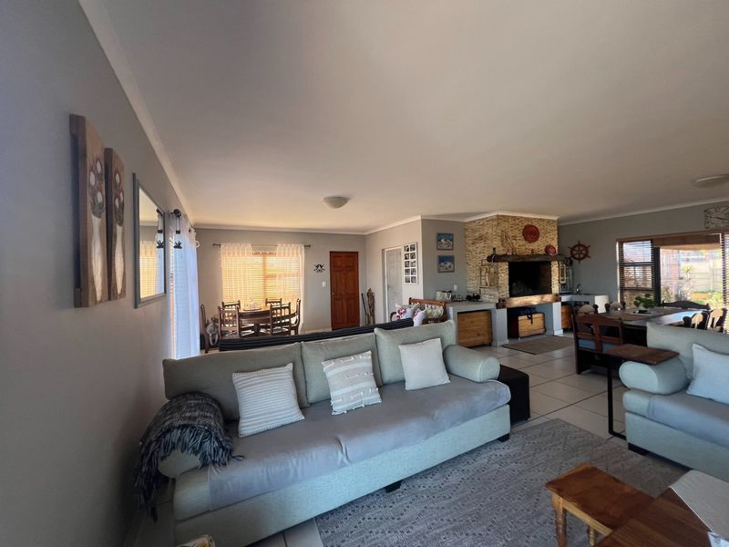 Spacious open-plan living and dining area featuring a prominent stone-clad built-in fireplace and neutral tiled flooring throughout.