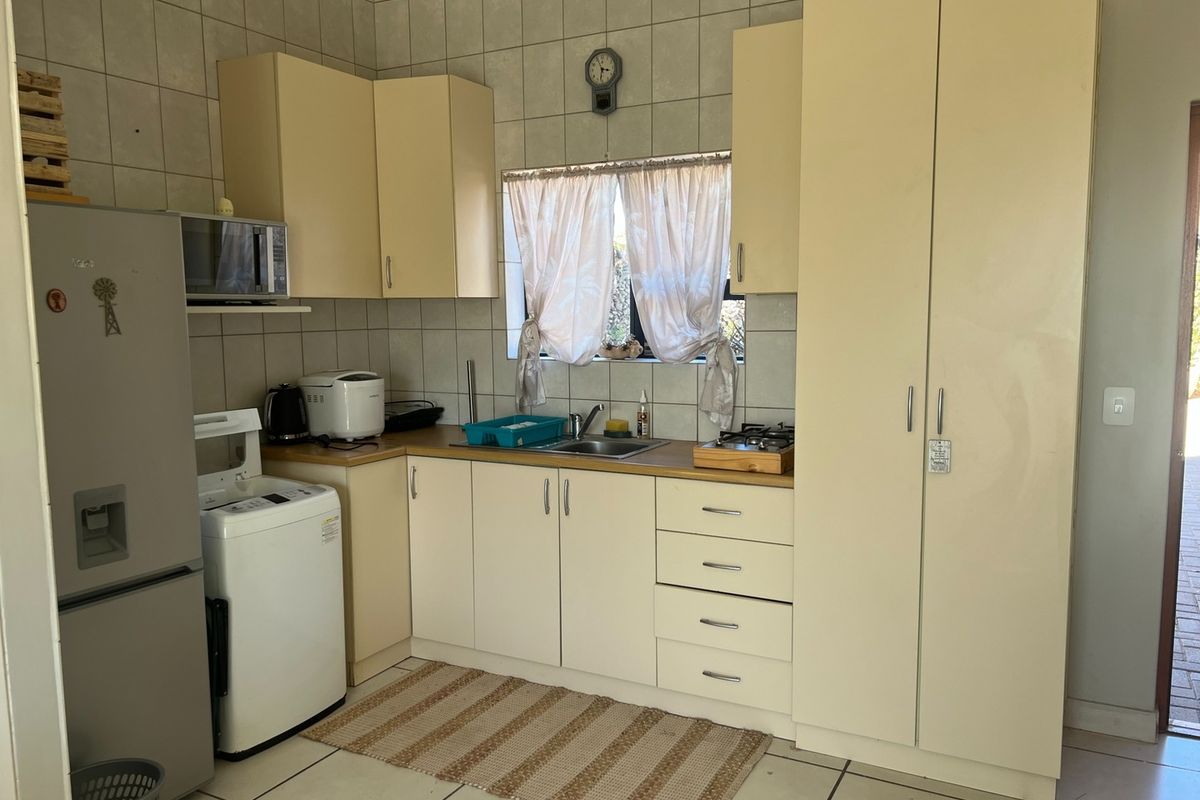A functional kitchen featuring built-in cabinetry, laminate countertops, a stainless steel sink, and tiled finishes throughout.