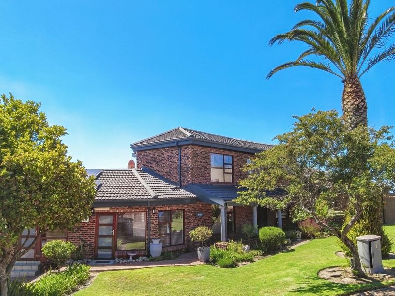 A well-maintained double-story face brick home featuring a tiled roof, solar panels, and a beautifully landscaped front garden with a paved walkway.