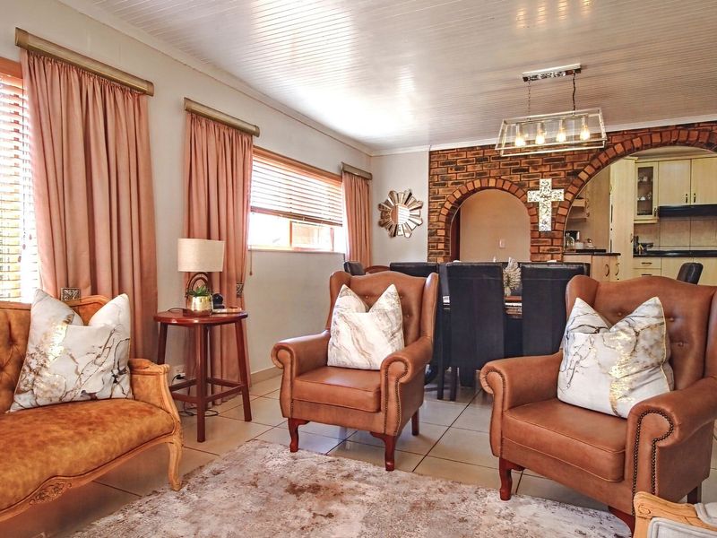 Open plan living and dining area featuring a distinctive brick archway leading to a functional kitchen with built-in cabinetry.