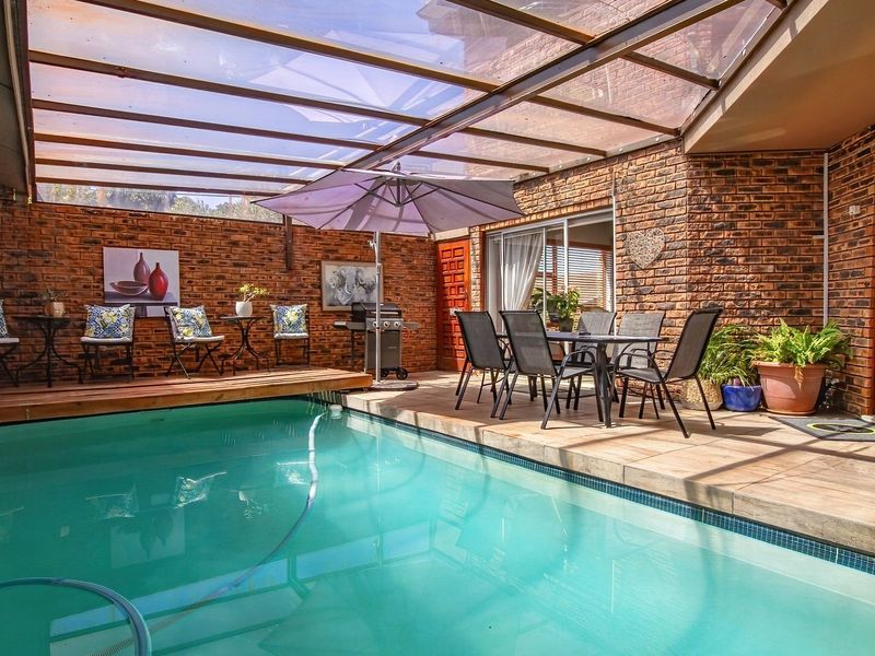 An enclosed pool area featuring a swimming pool, brick walls, and a translucent roof, providing a sheltered outdoor entertainment space.