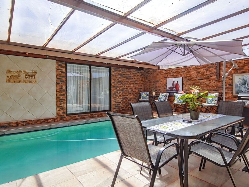 Enclosed outdoor entertainment area featuring a swimming pool, tiled flooring, and a protective polycarbonate roof, perfect for year-round use.