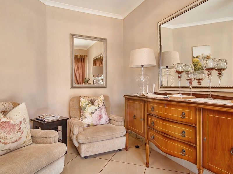A cozy living area featuring neutral wall tones, tiled flooring, and decorative wall-mounted mirrors, creating a warm and inviting atmosphere.
