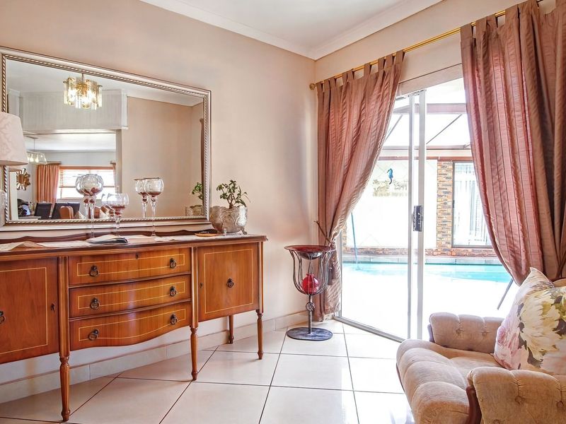A bright living area featuring tiled flooring and a sliding glass door providing direct access to the outdoor pool area.