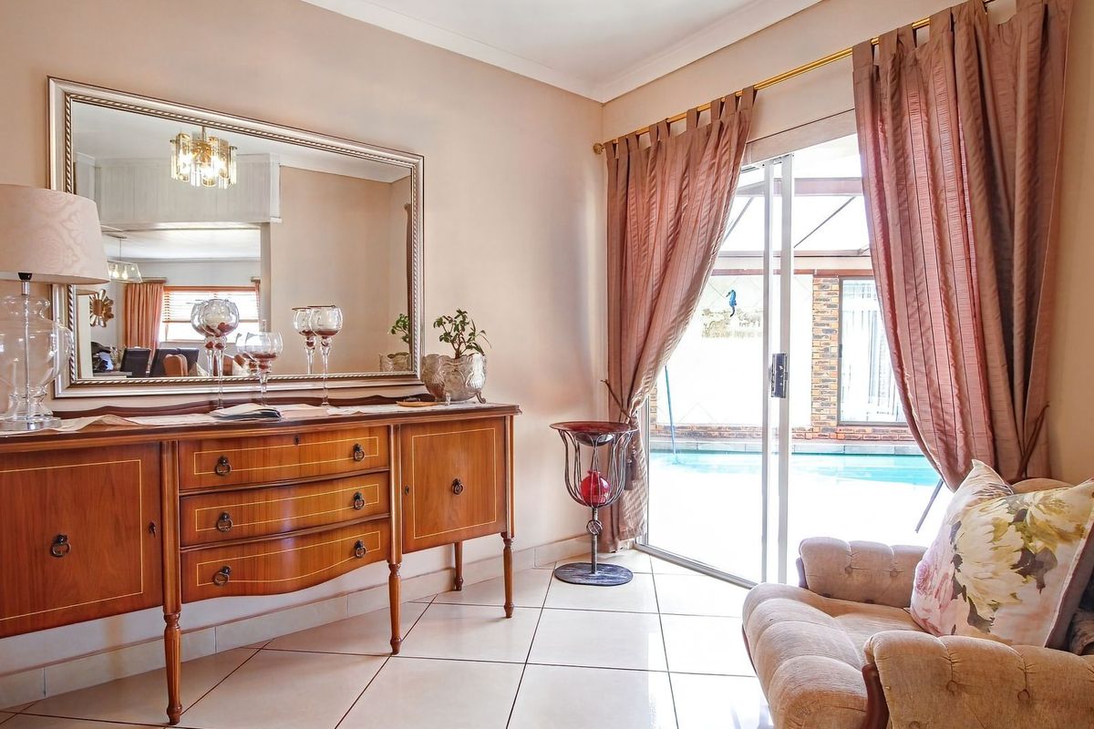 A bright living area featuring tiled flooring and a sliding glass door providing direct access to the outdoor pool area.