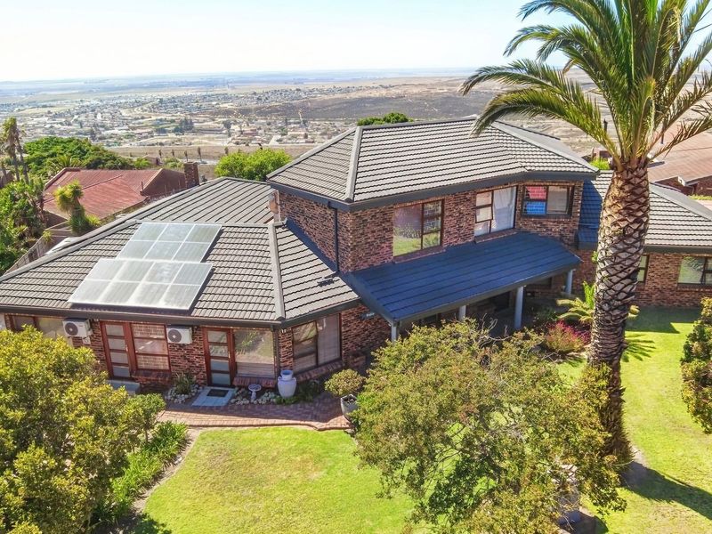 Aerial view of a double-story brick house featuring a tiled roof, installed solar panels, and a well-maintained garden with panoramic landscape views.