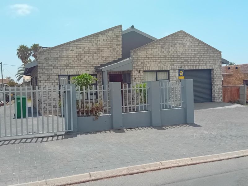 Front view of a face brick house featuring a paved driveway, secure metal fencing, and an integrated single garage.