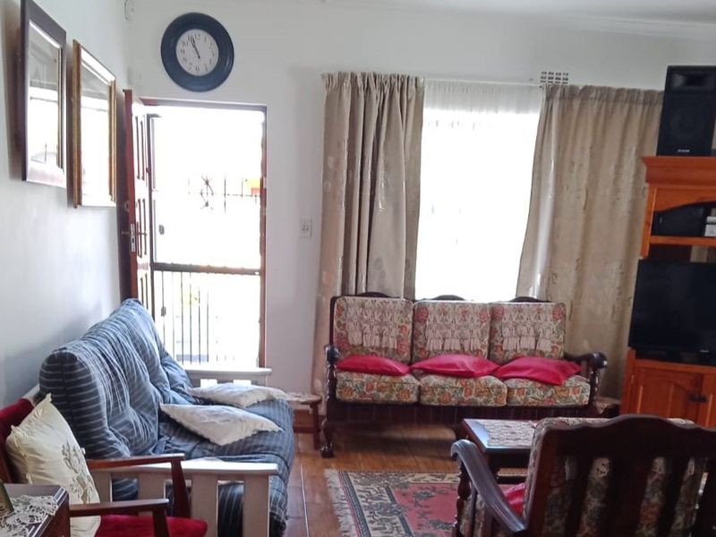 A living room area featuring tiled flooring, a security gate at the entrance, and window curtain rails.