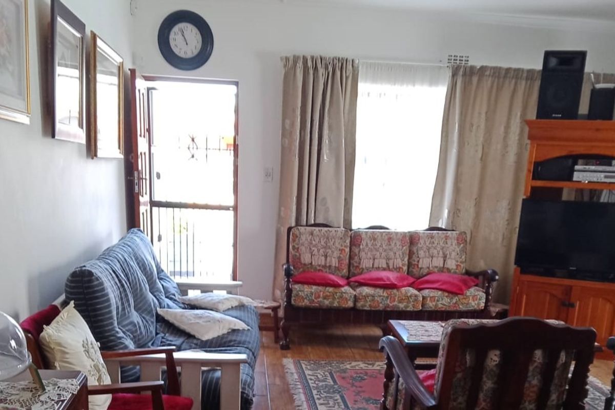 A living room area featuring tiled flooring, a security gate at the entrance, and window curtain rails.