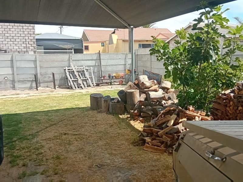 A covered outdoor patio area featuring a shade cloth canopy and a precast concrete boundary wall.