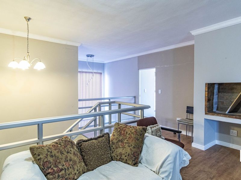 Open plan living area featuring a built-in fireplace, laminate flooring, and a staircase with a metal safety railing.