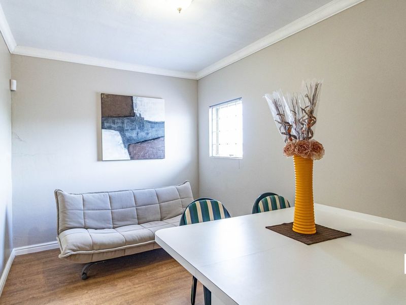 A functional living area featuring laminate flooring, coved ceilings, and a small security window, providing a neutral space ready for personalization.