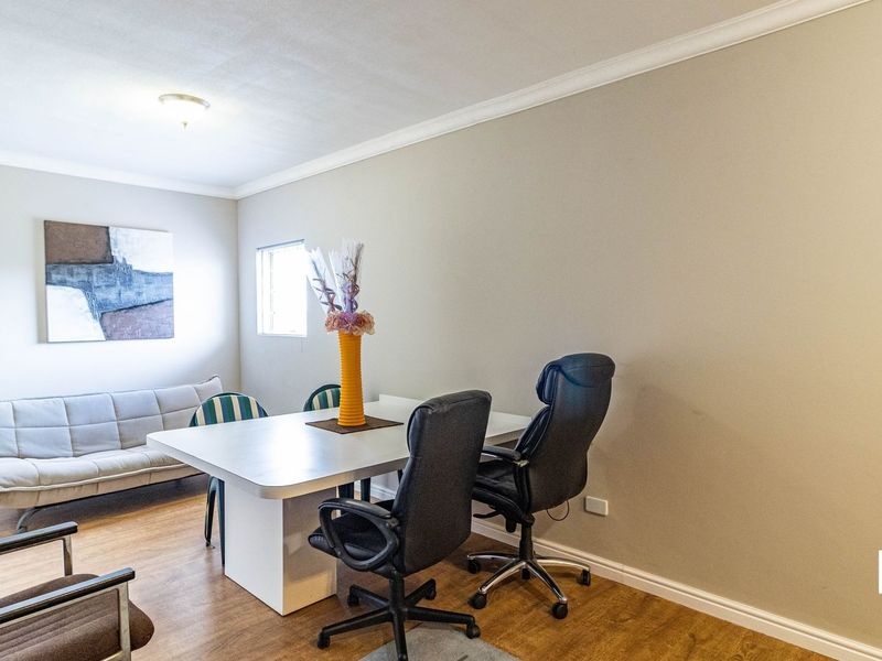 A functional office space featuring laminate flooring, neutral wall tones, and classic cove cornicing, suitable for a home workspace or study area.