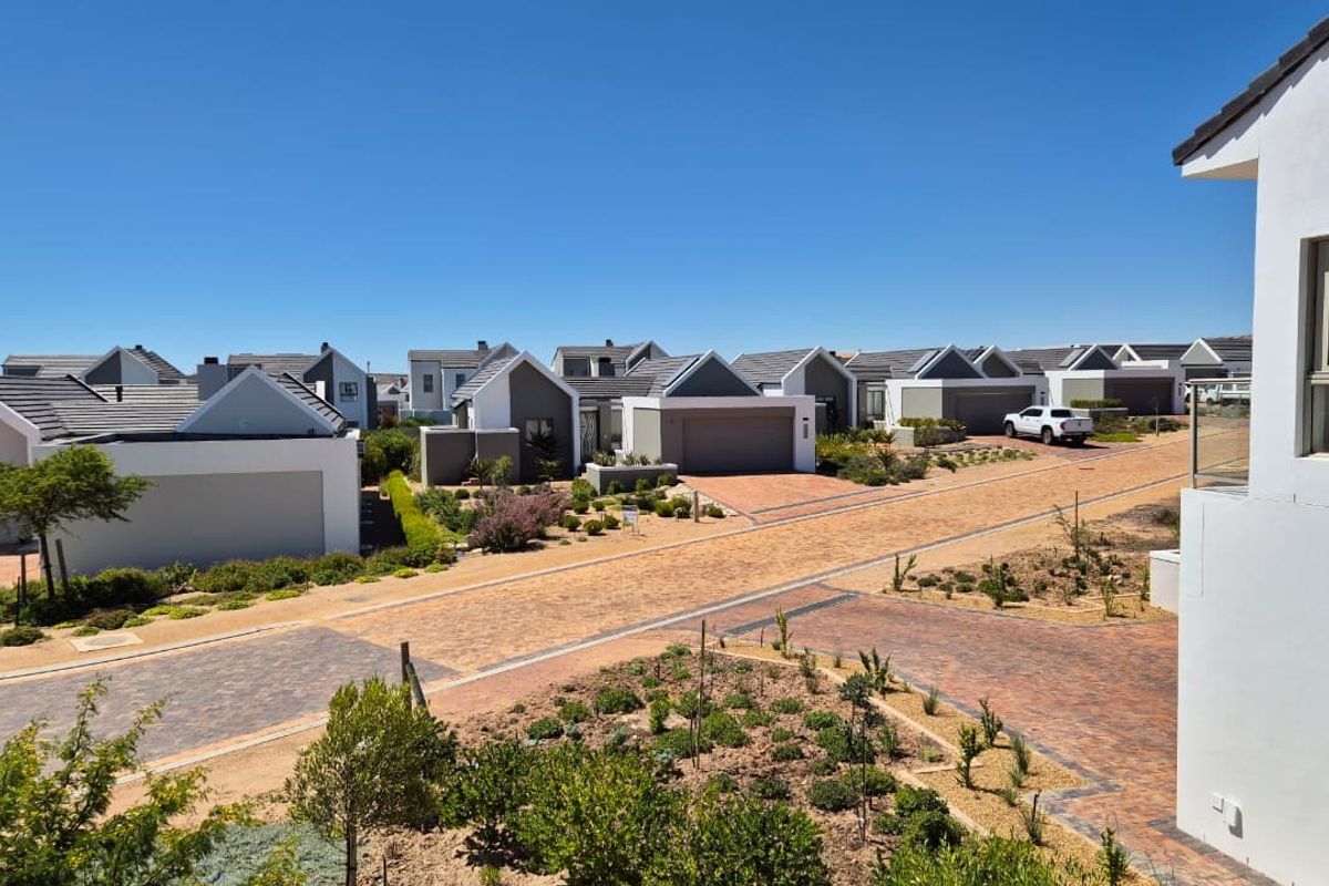 An elevated aerial view of a modern residential estate featuring paved driveways, landscaped gardens, and contemporary homes with tiled roofs.