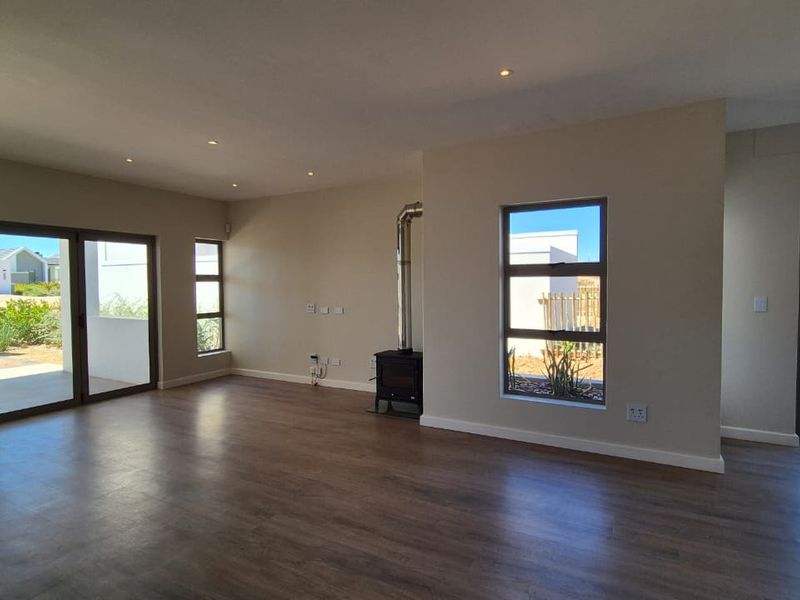 Spacious open-plan living area featuring modern laminate flooring, a built-in wood-burning fireplace, recessed lighting, and large aluminium sliding doors leading to the exterior.