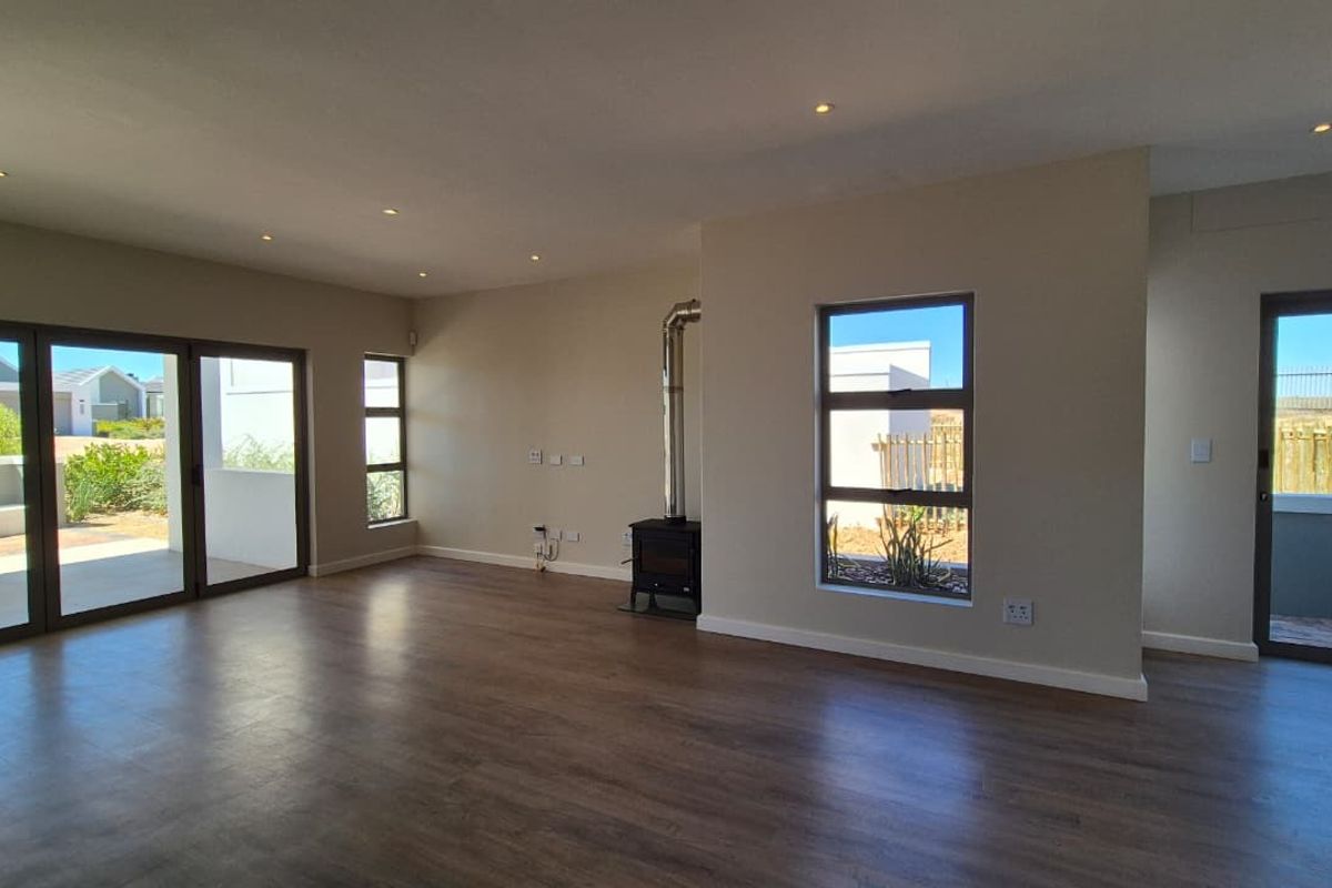 Spacious open-plan living area featuring modern laminate flooring, a built-in wood-burning fireplace, recessed lighting, and large aluminium sliding doors leading to the exterior.