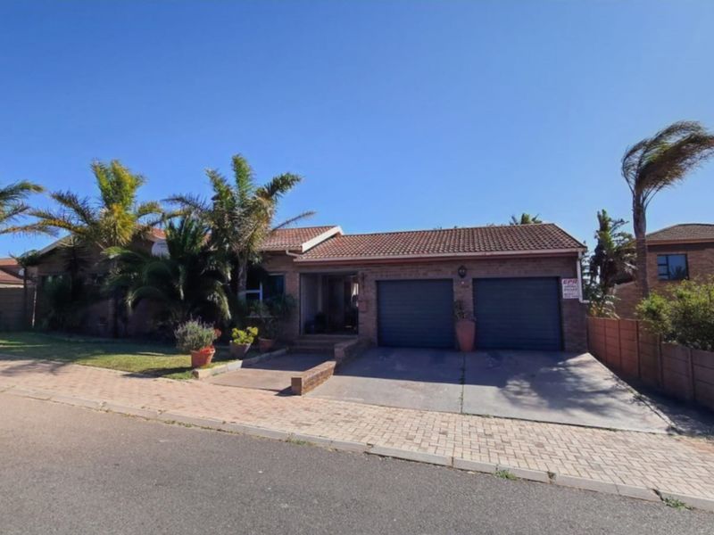 Front view of a single-story brick house featuring a double garage, paved driveway, and established garden.