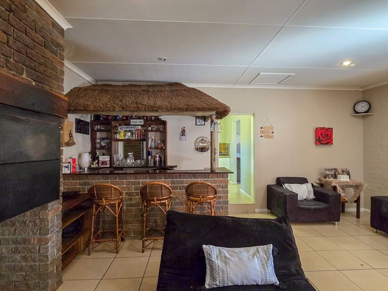 A rustic entertainment area featuring a built-in brick bar with a thatched canopy and a prominent brick fireplace.