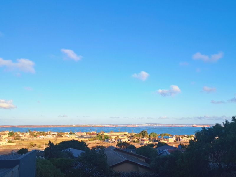 A scenic elevated view overlooking the coastal landscape, residential area, and the ocean horizon.